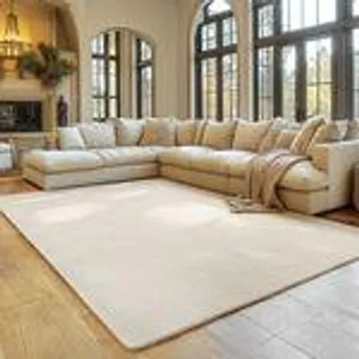 A spacious living room with a large sectional sofa and a cream-colored rug.
