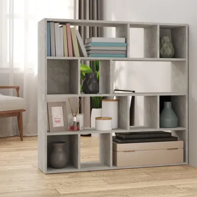 A concrete-effect bookshelf filled with books and decorative items, placed in a room with a chair and curtains visible.