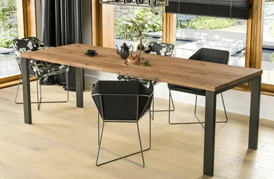 A dining table with chairs in a well-lit room with a view of a garden and water feature.