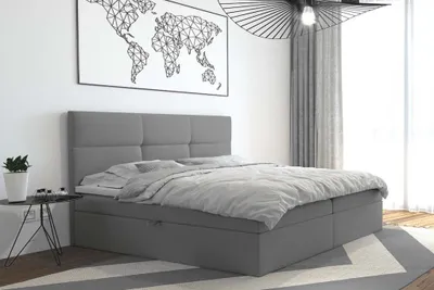 A bedroom scene with a bed, a world map poster, and a lamp.