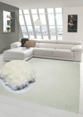 A modern living room with a white sectional sofa and a cream-colored shaggy rug.