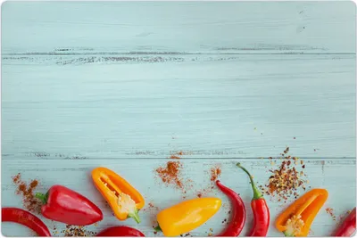 A collection of colorful peppers and spices arranged on a light blue wooden surface.