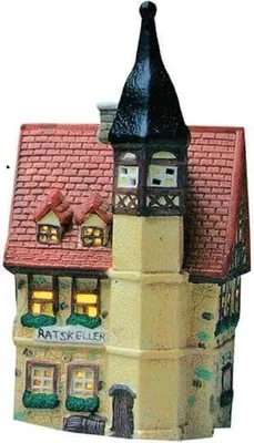 A ceramic miniature building, likely a decorative house or shop, with a tall, pointed black roof and red tiled roof sections. The building has illuminated windows and a sign that reads "RATSKELLEr".