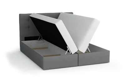 A bed with its mattress lifted to reveal storage space underneath.