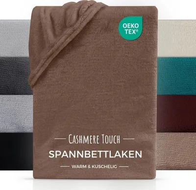 A folded brown fitted sheet with a label indicating 'Cashmere Touch Spannbettlaken' and an OEKO-TEX logo. Several other colors of fitted sheets are visible in the background.