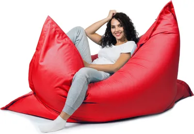 A woman is sitting on a large red beanbag chair.