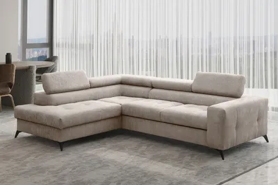 A sectional sofa is shown in a well-lit room with sheer curtains in the background.