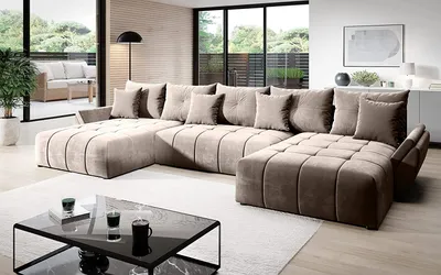 A large sectional sofa is arranged in a modern living room with a view of an outdoor patio through large glass doors.