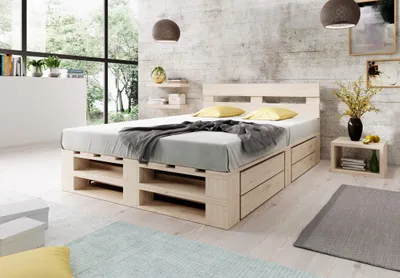 A bedroom setting with a wooden pallet bed, pillows, and a blanket.
