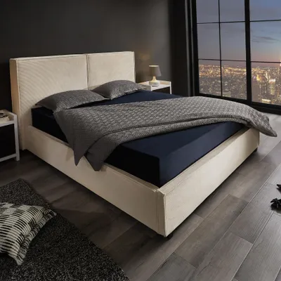 A modern bedroom with a large bed, city view through the window, and a bedside table.