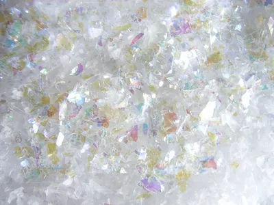 A close-up, overhead view of iridescent artificial snow flakes with colorful flakes mixed in.