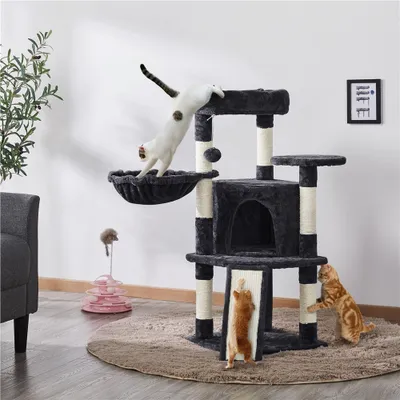 Two cats playing on a multi-level cat tree in a living room setting.