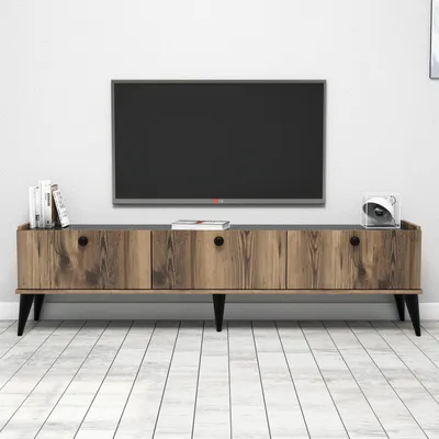 A TV stand with a television mounted above it, set against a white wall and on a light wooden floor.