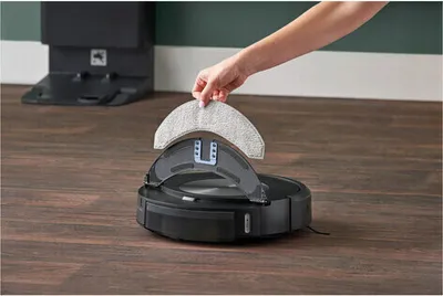 A person is holding a mop pad to attach to a robot vacuum cleaner.