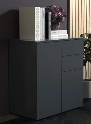 A dark gray sideboard with books and a floral arrangement on top, set against a dark wall and a slatted wooden panel.