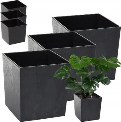 A group of black square planters are arranged in a stepped pattern, with one planter in the foreground containing a green plant.