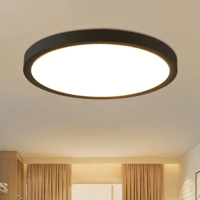 A modern, circular LED ceiling light with a black frame is mounted on a white ceiling.
