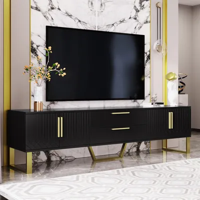 A black TV stand with gold accents and a large TV on top, set against a marble wall.