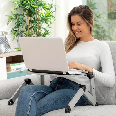 A woman is using a laptop on a portable table while sitting on a couch.