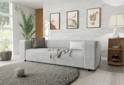 A modern living room with a light gray sofa, decorative pillows, a throw blanket, a round rug, a potted plant, and artwork on the wall.