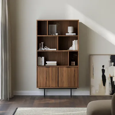 A modern living room with a wooden bookshelf filled with decorative items and books, next to a large abstract painting.