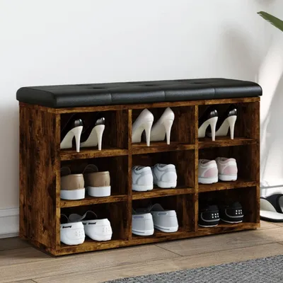 A shoe bench with multiple compartments, filled with various shoes, placed against a white wall.