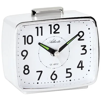 A white analog alarm clock with a silver top button.