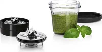 A set of blender attachments and a jar of pesto.