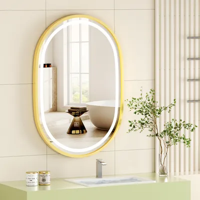 A modern bathroom with a gold-framed oval LED mirror above a sink.