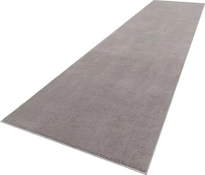A long, gray rug is shown from a diagonal angle against a white background.