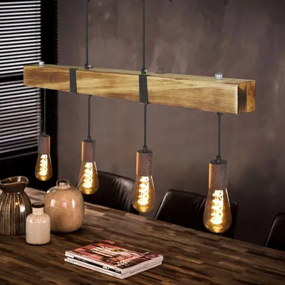 A vintage-style wooden beam pendant light with Edison bulbs hangs over a wooden dining table with decorative vases and a book.