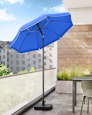 A blue patio umbrella is set up on a balcony with a table and chair.