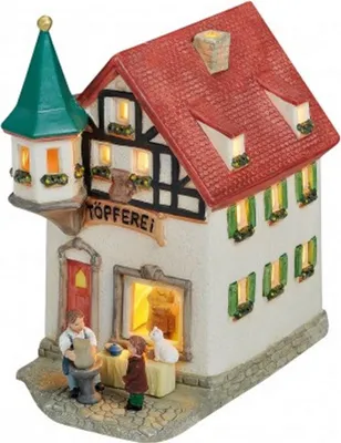 A miniature ceramic house depicting a pottery shop, with figures of a potter and a child, and a cat.