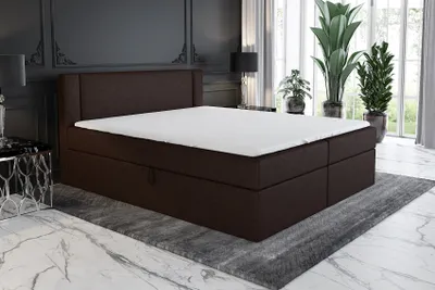A bedroom scene featuring a brown boxspring bed with a white mattress and topper.