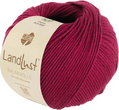 A ball of red yarn with a beige label wrapped around it.