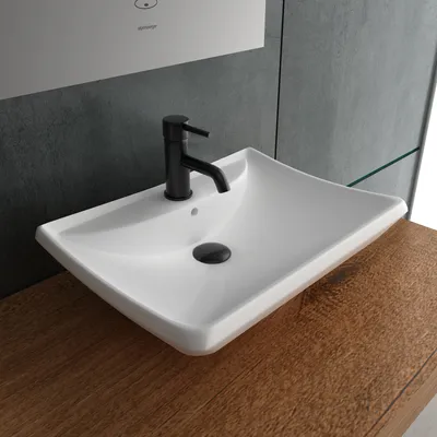 A white ceramic sink with a black faucet sits on a wooden countertop, with a gray tiled wall in the background.