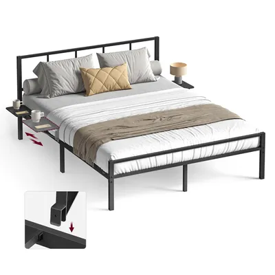 A black metal bed frame with a headboard, mattress, pillows, and a blanket. Two small side tables are attached to the headboard, one with a lamp and the other with two mugs.