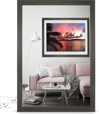 A living room scene with a pink sofa, a mirror, and a framed picture of a sunset.