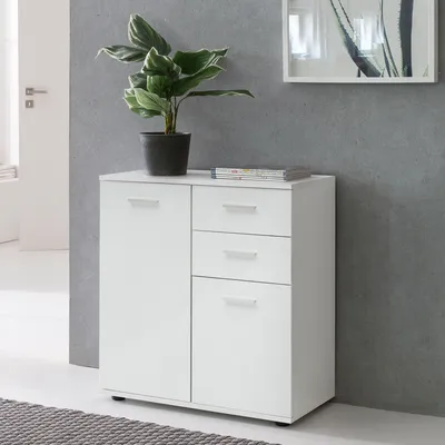 A white cabinet with drawers and doors, topped with a potted plant and magazines, against a gray wall.