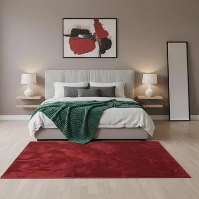 A bedroom scene with a bed, rug, and artwork.