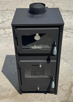 A black wood-burning stove with a chimney pipe on top, placed outdoors on a concrete surface.