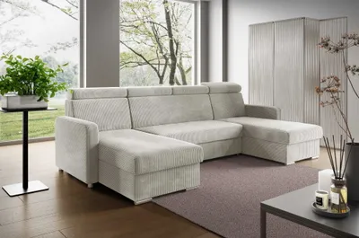 A modern living room with a large sectional sofa, a side table with a plant, and a decorative screen.