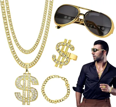 A flat lay of a gold-colored costume jewelry set including a dollar sign pendant necklace, a dollar sign ring, a bracelet, and aviator sunglasses, with a man wearing similar jewelry in the background.
