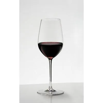 A single glass of red wine on a white surface.