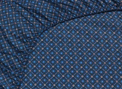 A close-up view of a dark blue fitted sheet with a repeating geometric pattern.