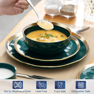 A hand is scooping soup from a bowl, which is part of a dinnerware set.