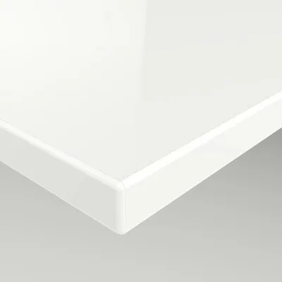 A close-up view of the edge of a white, glossy furniture panel.