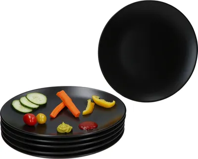 A stack of black plates with some vegetables and condiments on the top plate, and another black plate in the background.