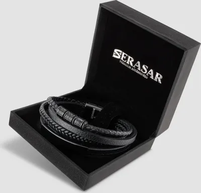 A black leather bracelet is displayed inside an open black gift box with the brand logo on the inside lid.