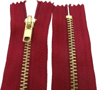 A close-up view of a dark red zipper with a gold-colored metal slider and teeth, shown against a white background.
